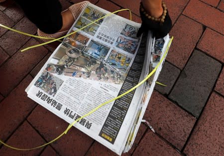 People take newspapers with headlines and pictures of the previous night's clashes between police and protesters in front of Wan Chai metro station in Hong Kong