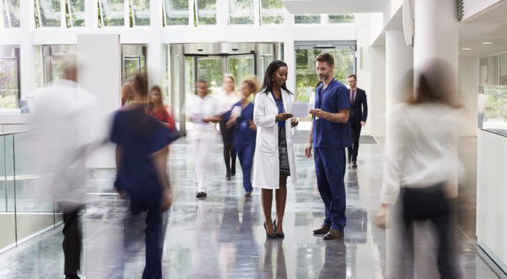 two doctors look over a piece of paper while standing in a hallway