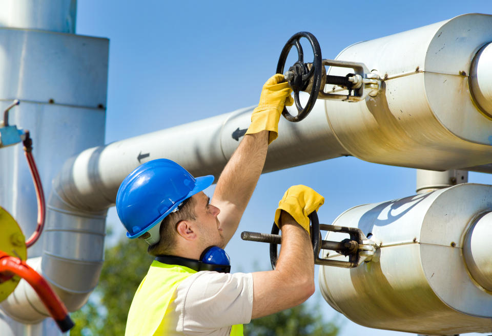 A man turning two valves on a pipeline