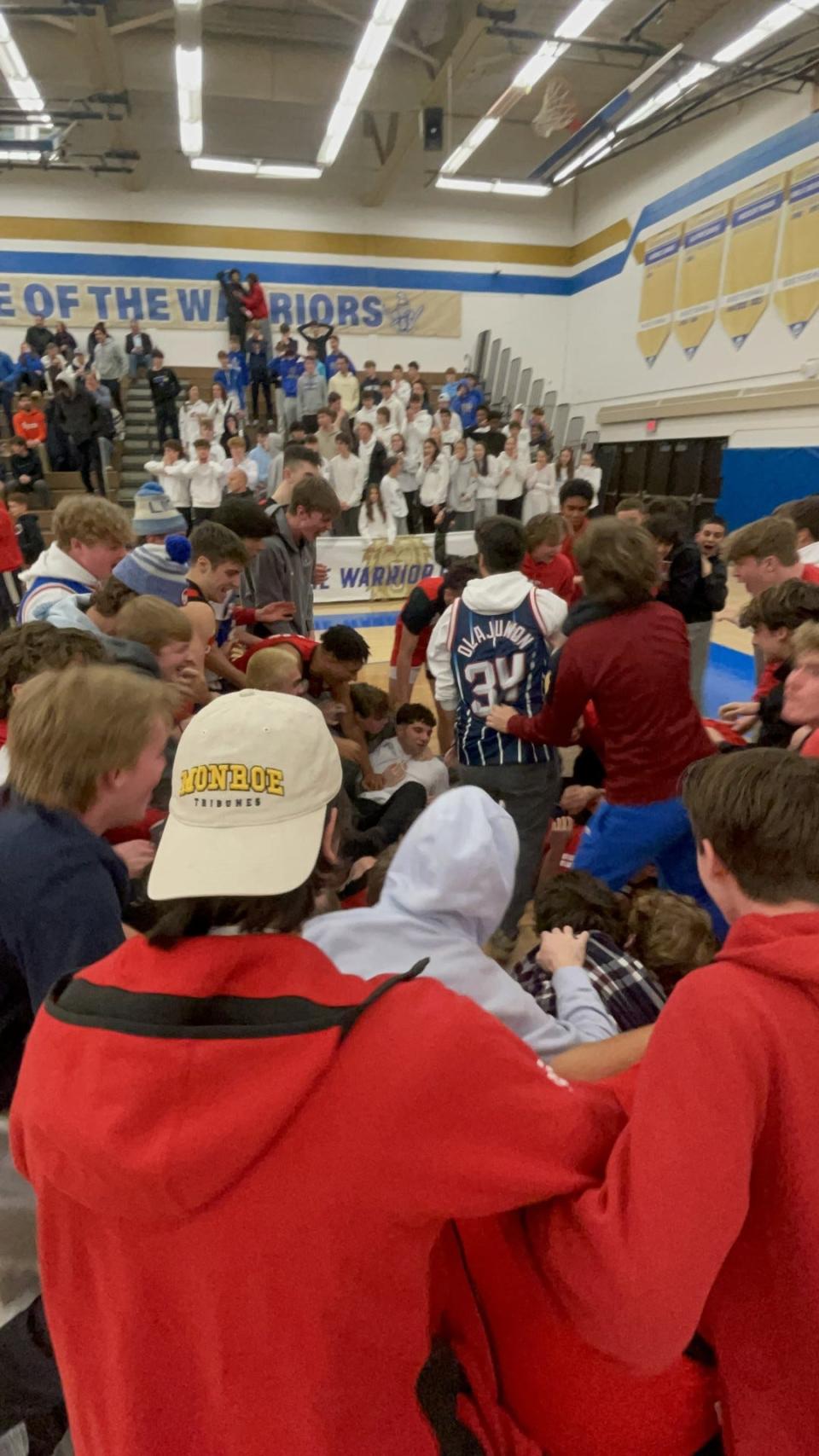 PANDEMONIUM! Penfield's student section stormed the court, piling on top of Trevor Hofer, 0, and his teammates after the Patriots' 51-50 win at Webster Schroeder in the Section V Class AA quarterfinals Saturday, Feb. 24, 2024. Hofer's game-winning layup went through the net as time expired.