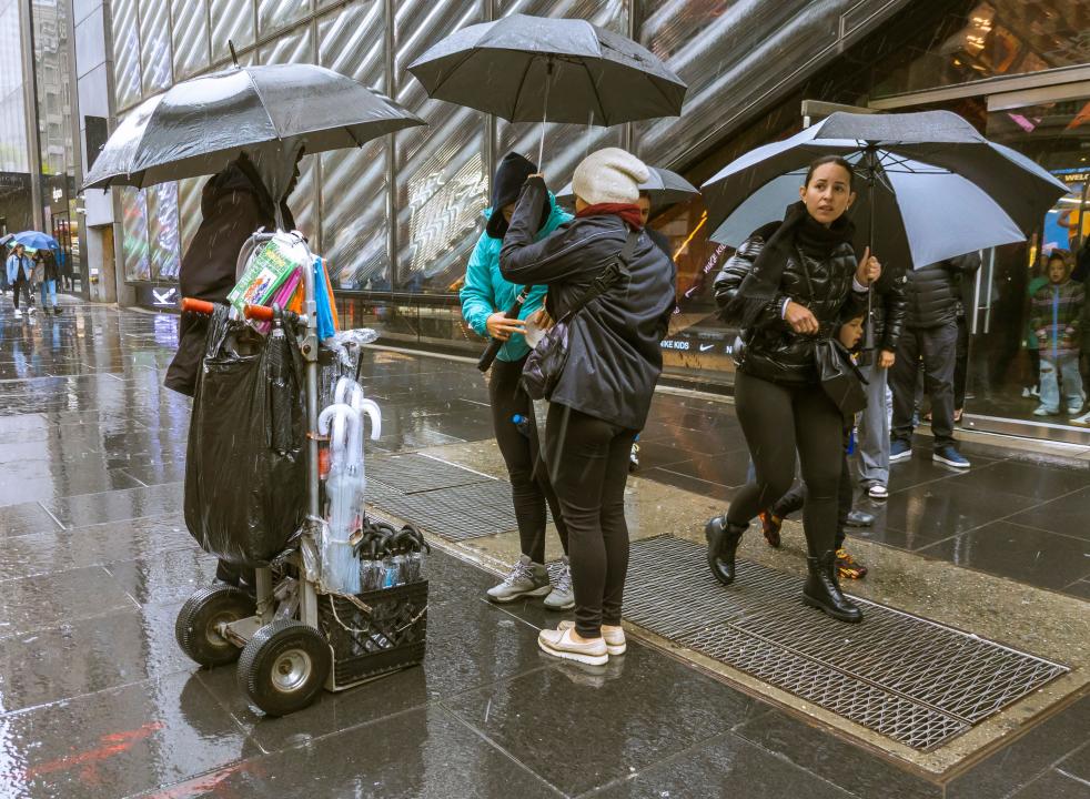 Tourists on Fifth Avenue in New York buy umbrellas from an entrepreneurial sidewalk vendor on Sunday, April 30, 2023. Weather from the Southeastern US and the Mississippi Valley has arrived in New York guaranteeing a sggy Sunday. (© Richard B. Levine)