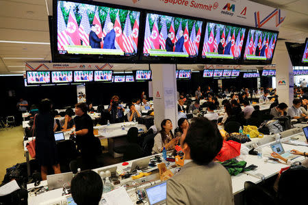 FILE PHOTO: A TV screen shows a news report about the meeting between U.S. President Donald Trump and North Korea's leader Kim Jong Un at a media center for the summit, in Singapore June 12, 2018. REUTERS/Tyrone Siu/File Photo