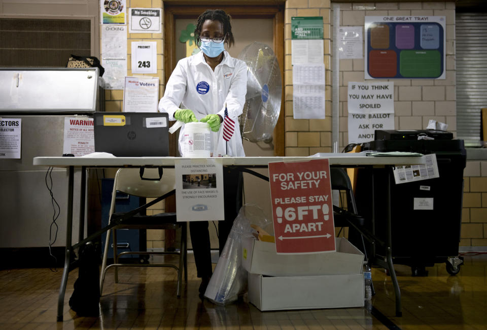 Debra Moore sanitizes her workspace during primary Election Day on Aug. 4, 2020, in Detroit. (Nicole Hester / Mlive.com via AP file)