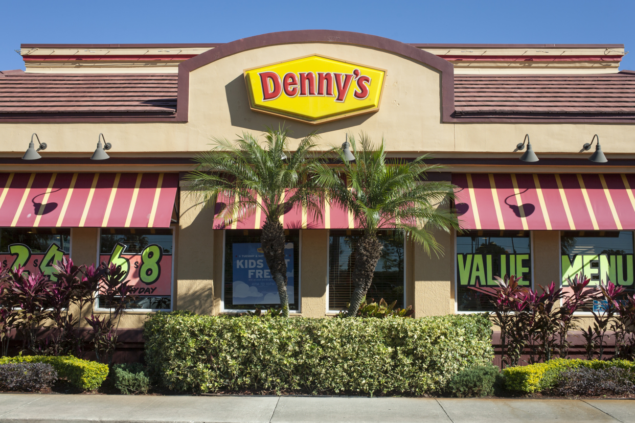 Closeup of front of a Denny's restaurant in Orlando, Florida, displaying value advertisements through the windows on a sunny day