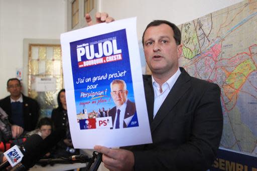 El vicepresidente del Frente Nacional (FN), pareja de su líder, Marine Le Pen, y candidato a alcalde de Perpiñán, Louis Alliot, mostrando el cartel electoral de su principal rival, el candidato de la UMP Jean-Marc Pujol, el 25 de marzo de 2014 (AFP/Archivos | Raymond Roig)