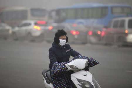 A man wearing a mask rides his electric bicycle along a street on a smoggy day in Zhengzhou, Henan province, China, November 30, 2015. Heavy smog and thick fog engulfed many parts of northern and eastern China on Monday, local media reported. REUTERS/Stringer