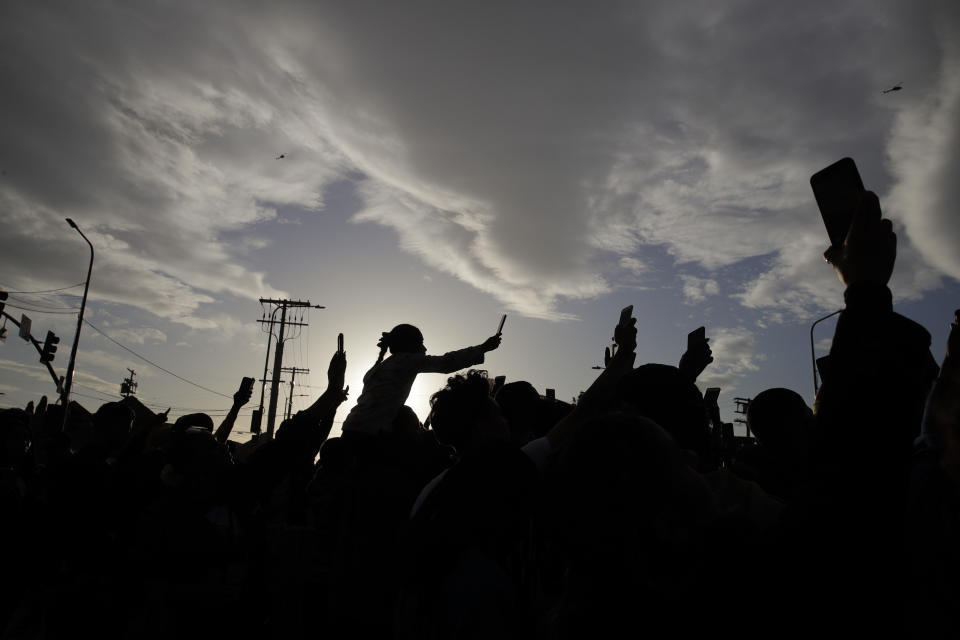 People hold up their smartphones to record as a hearse carrying the casket of slain rapper Nipsey Hussle passes by Thursday, April 11, 2019, in Los Angeles. Hussle was shot to death March 31 while standing outside his South Los Angeles clothing store, not far from where he grew up. (AP Photo/Jae C. Hong)