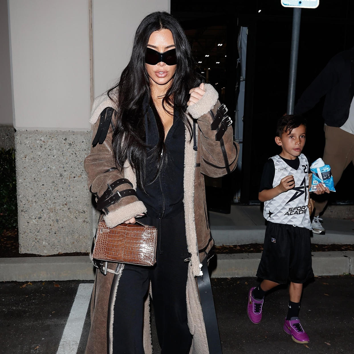  Kim Kardashian wearing a floor-length fur coat with an all-black outfit . 