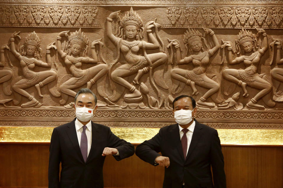 Chinese Foreign Minister Wang Yi, left, greets with Cambodian counterpart Prak Sokhonn in Phnom Penh, Cambodia, Sunday, Sept. 12, 2021. Wang is visiting Cambodia, where's he expected to meet with Prime Minister Hun Sen and other officials to discuss COVID-19 and other regional issues. (Kith Serey/Photo Photo via AP)