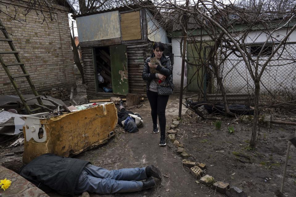 FILE - Ira Gavriluk holds her cat as she walks past the corpses of her husband and her brother, who were killed in Bucha, on the outskirts of Kyiv, Ukraine, April 4, 2022. The scenes that emerged from this town near Kyiv a year ago after it was retaken from Russian forces have indelibly linked its name to the savagery of war. (AP Photo/Rodrigo Abd, File)