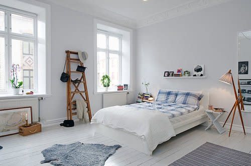 Wooden accents, textured rugs, and patterned fabrics add warmth against the all-white base of this bedroom in an eclectic Swedish apartment. Source: Alvhem Estate & Interior