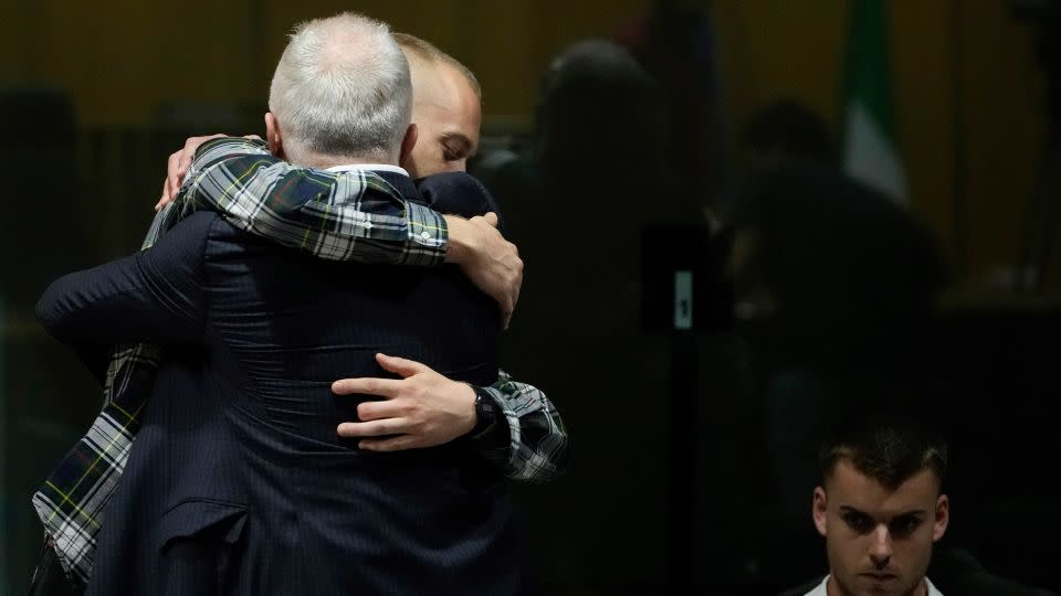 Ethan Elder, back to camera, hugs his son Finnegan Lee Elder before the reading of the judgment in Rome, Italy, on July 3, 2024. At right sits Gabriel Natale Hjorth. - Alessandra Tarantino/AP