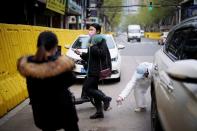 Un conductor con un traje protector desinfecta a una mujer en una calle de Wuhan, provincia de Hubei, el epicentro del brote de la enfermedad coronavirus de China (COVID-19), el 3 de abril de 2020