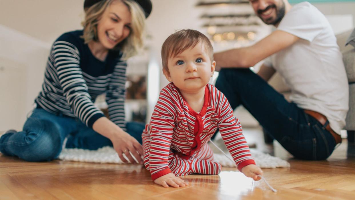 Photo of a young family who enjoy their moments together at home while little baby is learning to crawl.