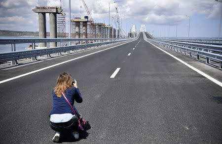 A woman takes pictures prior to a ceremony opening a bridge, which was constructed to connect the Russian mainland with the Crimean Peninsula across the Kerch Strait, May 15, 2018. Alexander Nemenov/Pool via REUTERS