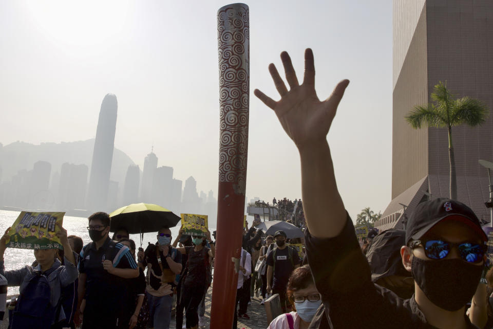 A pro-democracy protester raises his hand to symbolize the five demands of the pro-democracy movement as they march against the Central district scenic during a rally at the Water Front in Hong Kong, Sunday, Dec. 1, 2019. Pro-democracy protesters renewed pressure on the Hong Kong government Sunday with three separate marches, appealing to President Donald Trump for help and demanding that police stop using tear gas. (AP Photo/Ng Han Guan)