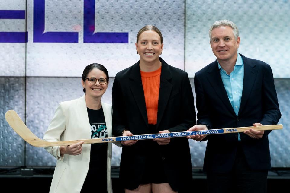 Ashton Bell, centre, poses for a photo with former Canadian professional soccer player Diana Matheson, left, after being selected eighth overall by Ottawa during in the inaugural Professional Women’s Hockey League draft on Sept. 18, 2023.