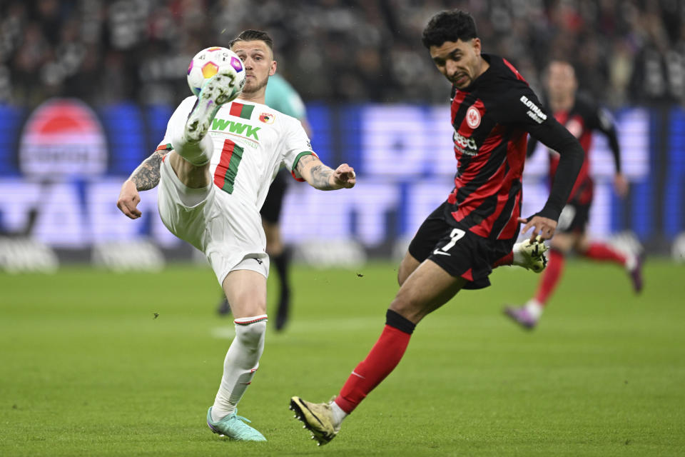 Augsburg's Jeffrey Gouweleeuw, left, controls the ball as Frankfurt's Omar Marmoush closes induring the German Bundesliga soccer match between Eintracht Frankfurt and FC Augsburg, in Frankfurt, Germany, Friday, April 19, 2024. (Arne Dedert/dpa via AP)