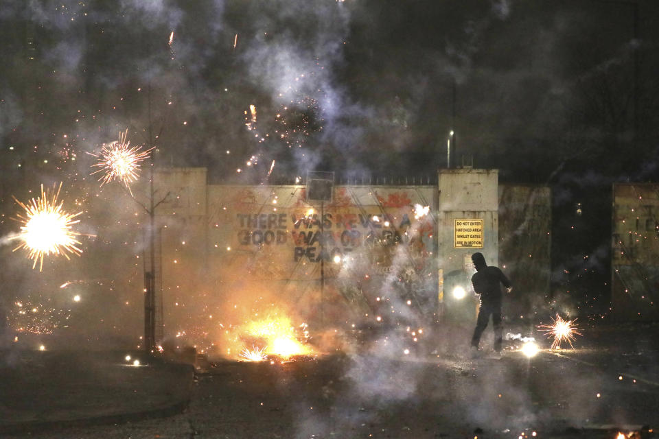 FILE - In this Wednesday, April 7, 2021 file photo, a firework explodes as Nationalist and Loyalist rioters clash with one another at the peace wall on Lanark Way in West Belfast, Northern Ireland. The chaotic scenes during a week of violence on the streets of Northern Ireland have stirred memories of decades of Catholic-Protestant conflict, known as “The Troubles.” A 1998 peace deal ended large-scale violence but did not resolve Northern Ireland’s deep-rooted tensions. (AP Photo/Peter Morrison, File)