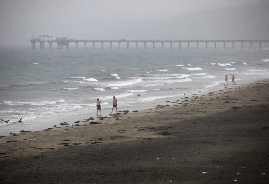 People walk along the coast at La Jolla Shores as Tropical Storm Hilary arrives on Sunday, Aug. 20, 2023, in San Diego. (K.C. Alfred/The San Diego Union-Tribune via AP)