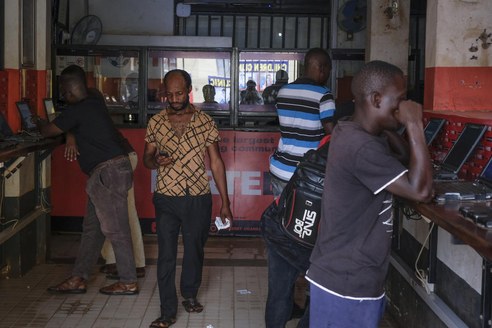 Moses Ssali, center, looks at his phone after placing bets at the Fortebet sports betting shop in the Ntinda area of the capital Kampala, Uganda, Tuesday, Dec. 6, 2022. In Uganda, an East African country where annual income per capita was $840 in 2020, many see sports betting as a path to survival and perhaps even prosperity. (AP Photo/Hajarah Nalwadda)