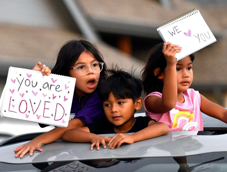 Children wave homemade signs of support as they parade past the Molina home Tuesday.