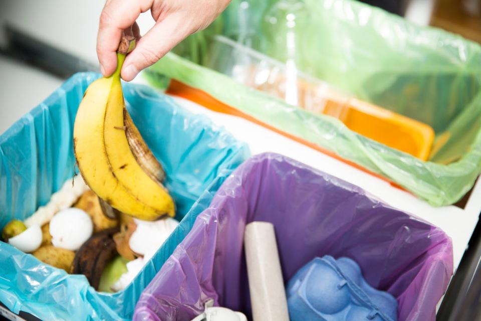 garbage cans and recycling in kitchen draw with hand tossing out banana peel