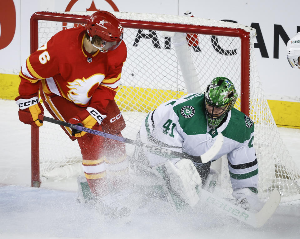 Dallas Stars goalie Scott Wedgewood, right, freezes the puck as Calgary Flames forward Martin Pospisil showers him with snow during the second period of an NHL hockey game in Calgary, Alberta, Thursday, Nov. 30, 2023. (Jeff McIntosh/The Canadian Press via AP)