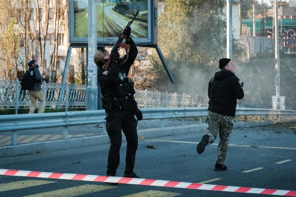 A police officer fires a rifle at a flying drone on a Kyiv street.