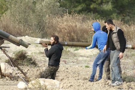 Rebel fighters load a Grad long distance shell before firing it towards forces loyal to Syria's president Bashar Al-Assad located in the city of Jableh at the Syrian coast, from Jabal al-Akrad area in Syria's northwestern Latakia province December 4, 2014. REUTERS/Alaa Khweled