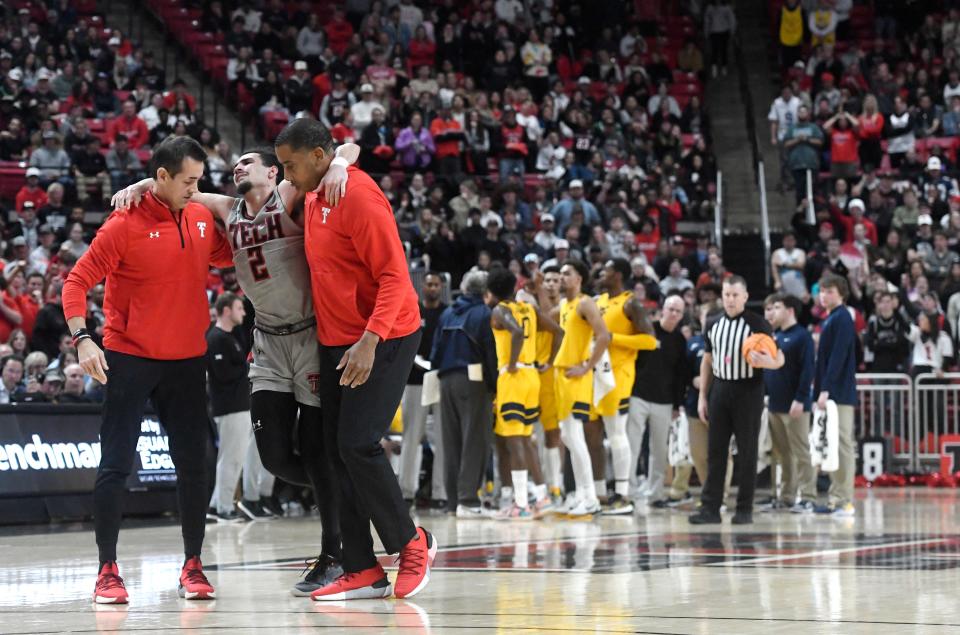 Texas Tech strength and conditioning coach Darby Rich, left, and athletic trainer Mike Neal, right, assist Pop Isaacs during the West Virginia basketball game, Wednesday, Jan. 25, 2023, at United Supermarkets Arena. 
