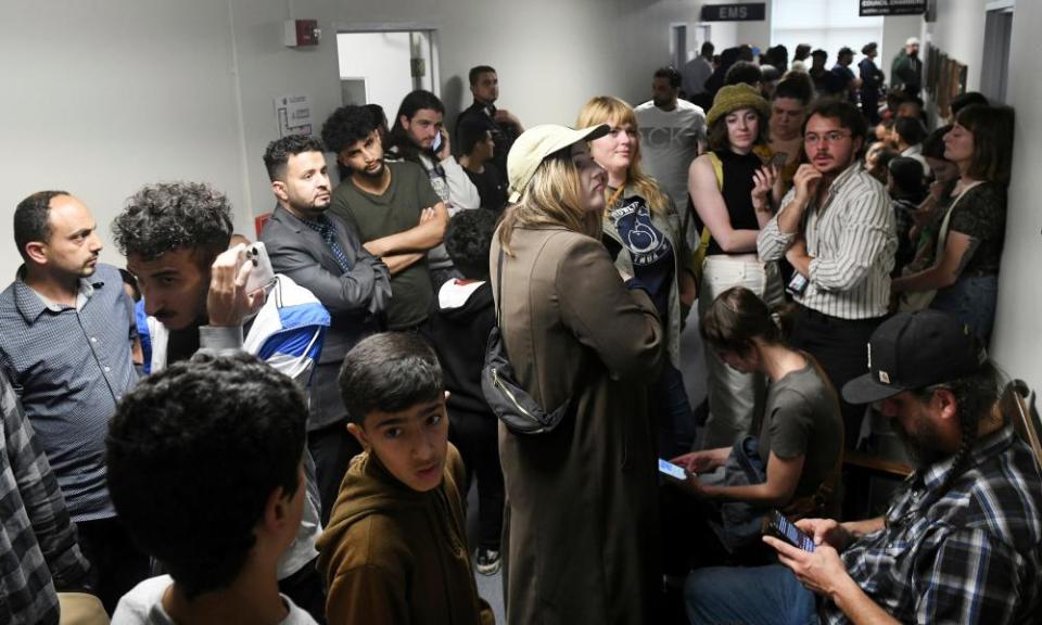 People who could not get into the Hamtramck city council chambers try to listen via YouTube or on the monitor in the hallway during the city council meeting at City Hall in Hamtramck on Tuesday.