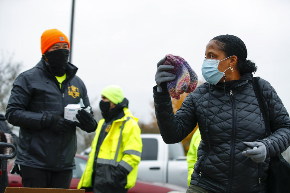 Election Defender volunteers hand out knitted hats to voters, including one at right, during early voting for the Senate runoff election at Ron Anderson Recreation Center, Thursday, Dec. 17, 2020, in Powder Springs, Ga. (AP Photo/Todd Kirkland)