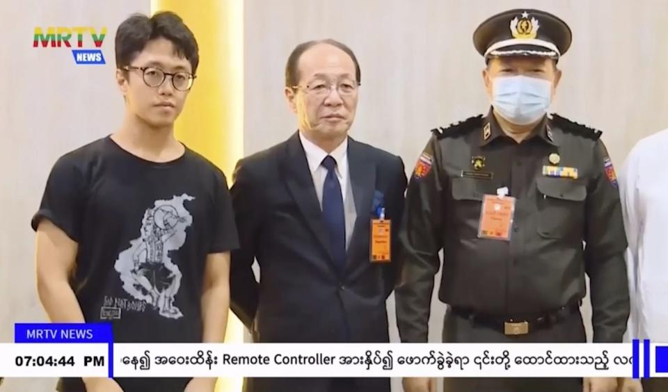 In this image taken from video by Myanmar state broadcaster MRTV, Japanese national Toru Kubota, left, poses with unidentified officials at the Yangon International Airport in Yangon, Myanmar on Thursday, Nov. 17, 2022. Myanmar’s military-controlled government says it is releasing and deporting an Australian academic, a Japanese filmmaker, an ex-British diplomat and an American as part of a broad prisoner amnesty marking the country’s National Victory Day. (MRTV via AP)