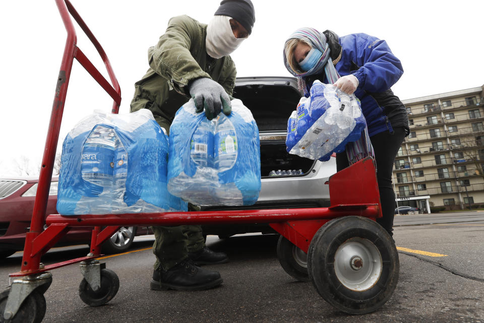 Rabbi Yosef Chesed, left, helps unload bottled water being donated from Lorie Lutz, right, at the Brightmoor Connection Food Pantry in Detroit, Monday, March 23, 2020. The global coronavirus pandemic has brought water shutoffs in Detroit and in communities across the nation into sharp focus again amid a crucial time when officials are urging Americans to practice social distancing and basic hand-washing techniques to stop the spread of COVID-19. (AP Photo/Paul Sancya)