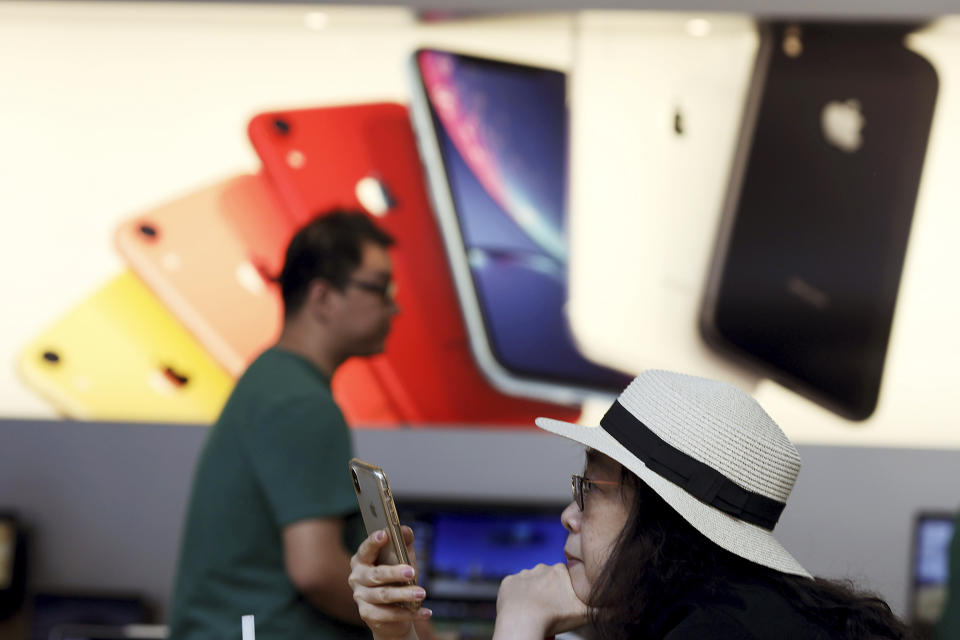 FILE - In this Friday, May 10, 2019, file photo, a customer looks at her iPhone at an Apple store in Beijing. Few U.S. companies are more vulnerable to a trade war with China than Apple. The company relies on factories in China to assemble the iPhones that generate most of its profits; it has also cultivated a loyal following in the country. (AP Photo/Ng Han Guan, File)