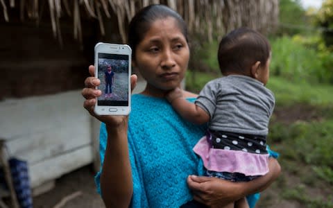 Claudia Maquin, 27, shows a photo of her daughter, Jakelin, at her home in Raxruha, Guatemala  - Credit: Oliver de Ros/AP