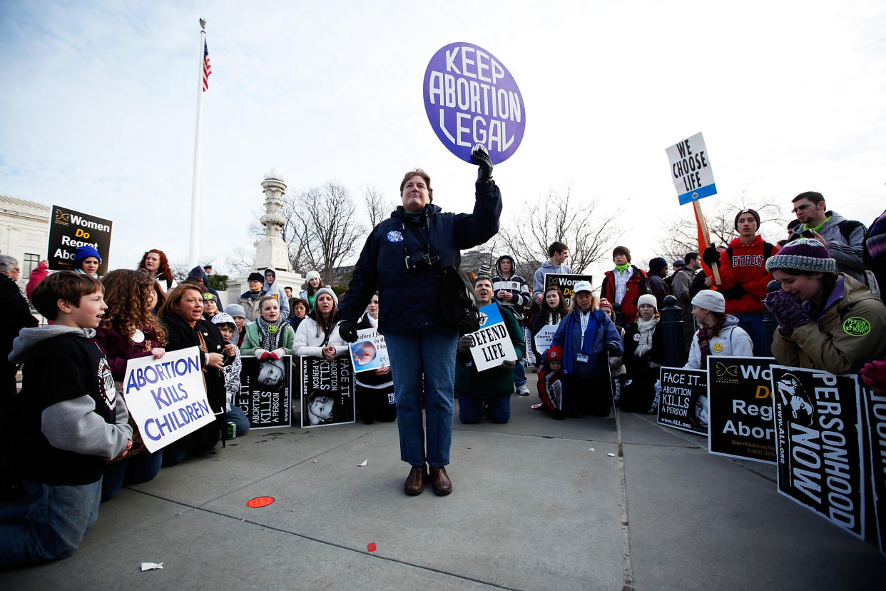 Anti-abortion activists kneel down and pray as they surround abortion rights activist Luanne Smith of Burke, Va., during the annual 