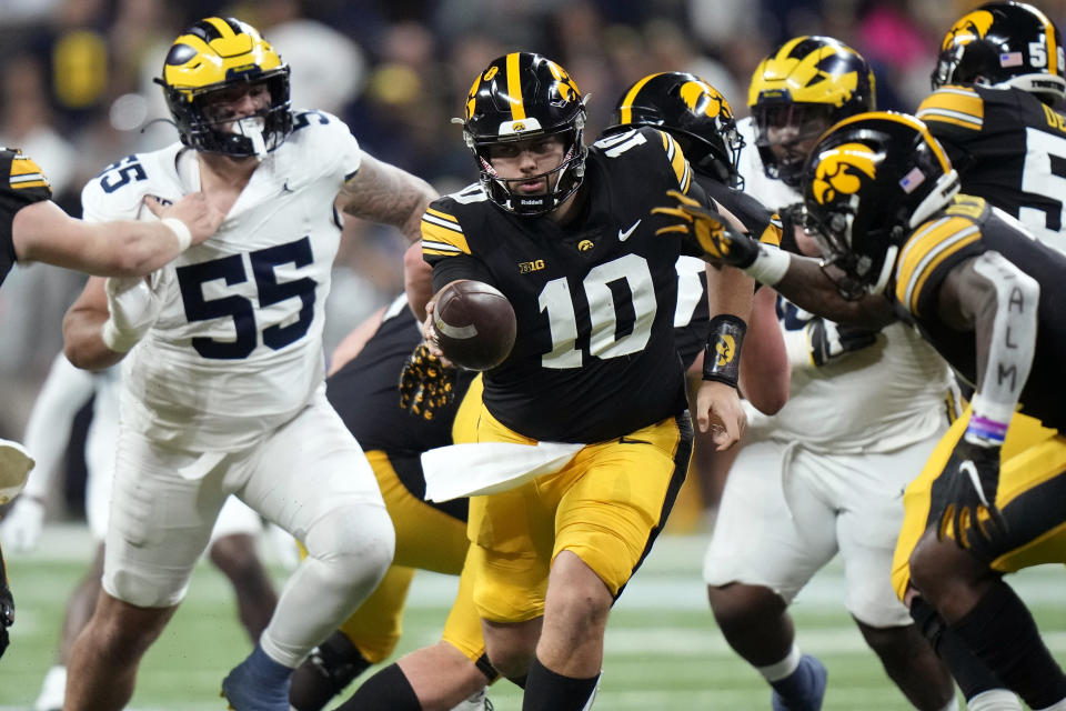 Iowa quarterback Deacon Hill (10) looks to hand the ball off in front of Michigan defensive lineman Mason Graham (55) during the first half of the Big Ten championship NCAA college football game, Saturday, Dec. 2, 2023, in Indianapolis. (AP Photo/AJ Mast)