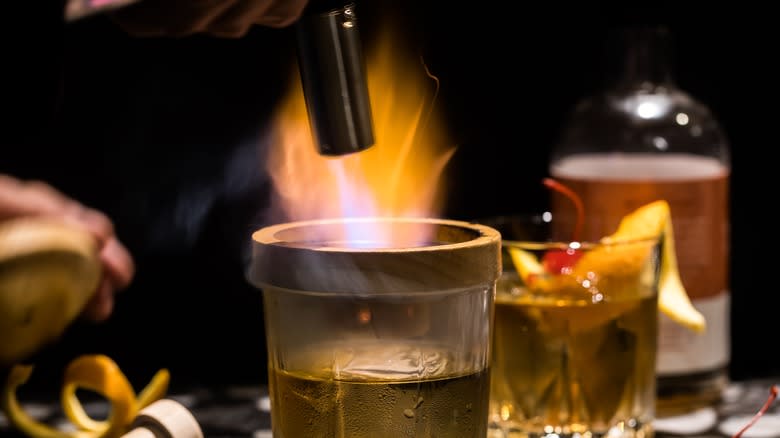 cocktail with blow torch and wooden rim