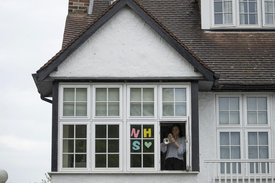 National Youth Orchestra of Great Britain trumpet player Tian Hsu, 16, takes part in a socially distanced orchestra performance of Beethoven's "Ode to Joy" from a window of her home in south west London, during the lockdown to prevent the spread of coronavirus, Friday, April 17, 2020. The members of the National Youth Orchestra, took part in the coordinated Ode to Joy-a-thon on Friday, each giving their own 40 second performance, with photos or videos taken by their families to share on social media. They dedicated the performance to the National Health Service staff, key workers, and people who feel isolated in their homes during the lockdown. (AP Photo/Matt Dunham)