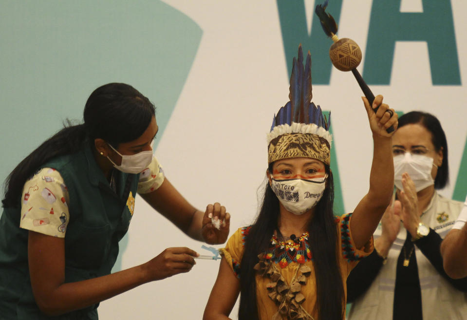 FILE - In this Jan. 18, 2021 file photo, Healthcare worker Vanda Ortega, from the Witoto Indigenous group and dressed in traditional clothing, is the first woman to receive the COVID-19 vaccine produced by China's Sinovac Biotech Ltd, during the start of the vaccination program in Manaus, Amazonas state, Brazil. Navigating complex waterways to reach remote communities in Brazil’s Amazon is only the first challenge for health workers vaccinating Indigenous and riverine people against COVID-19. Upon arrival, they face something they never anticipated: people refusing to take the shot. (AP Photo/Edmar Barros, File)