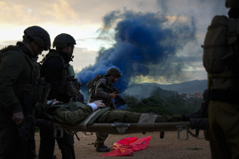 Israeli soldiers run as they carry a stretcher towards a military helicopter during an exercise simulating evacuation of wounded people in northern Israel, near the border with Lebanon, Tuesday, Feb. 20, 2024. (AP Photo/Ariel Schalit)