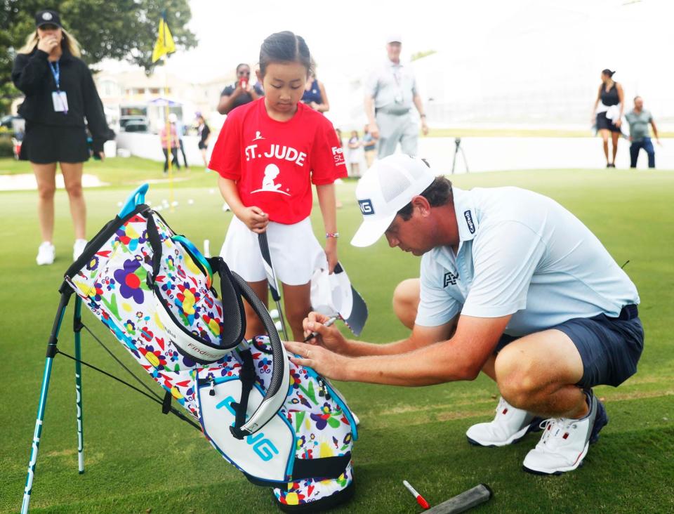 Taylor Montgomery authographs St. Jude patient Maelin-Kate's new golf bag during the TaylorMade/PING putt-around on Aug. 8, 2023, at TPC Southwind in Memphis. The FedEx St. Jude Championship is Aug.10-13 at TPC Southwind.