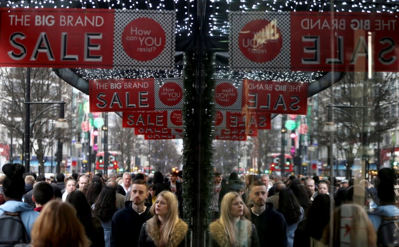 Shoppers are reflected in a store window as they pass sales advertisements on Oxford Street in London, Britain, December 26, 2015. REUTERS/Neil Hall/File Photo