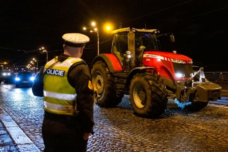 A police officer looks on as a farmer drives his tractor to protest rising costs and EU environmental regulations. Deml Ondøej/CTK/dpa