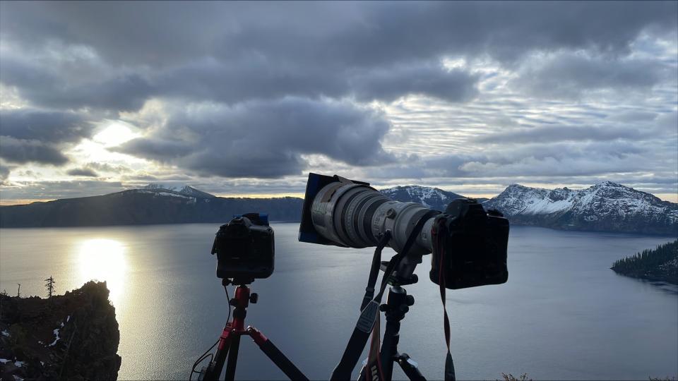 Cameras are set up along the rim of Crater Lake as heavy clouds and some sun breaks appear before the eclipse on Saturday, Oct. 13, 2023.