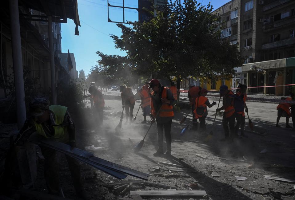 Communal workers clean an area at the site of an apartment building destroyed during a Russian missile strike (REUTERS)