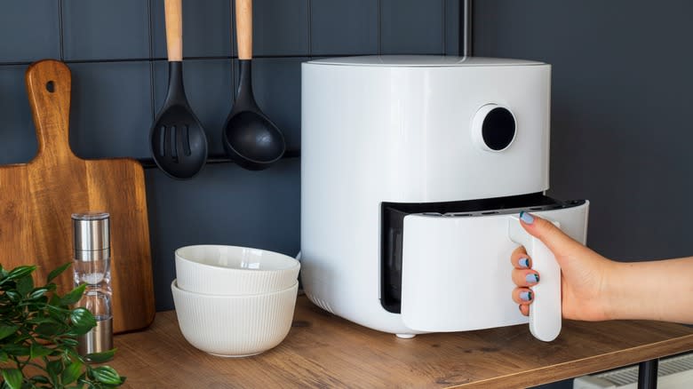 Person opening air fryer appliance