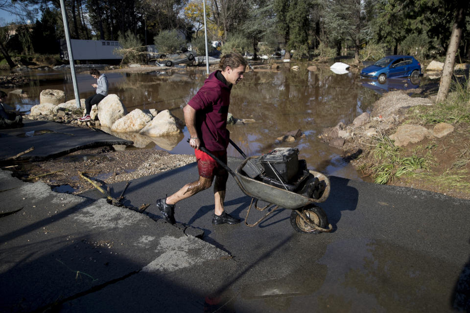 Un hombre lleva unos suministros en un camino afectado por inundaciones en la localidad de Roquebrune-sur-Argens, el lunes 2 de diciembre de 2019. (AP Foto/Daniel Cole)